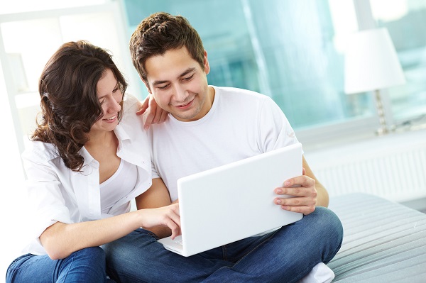 Tilt up of couple using laptop at home